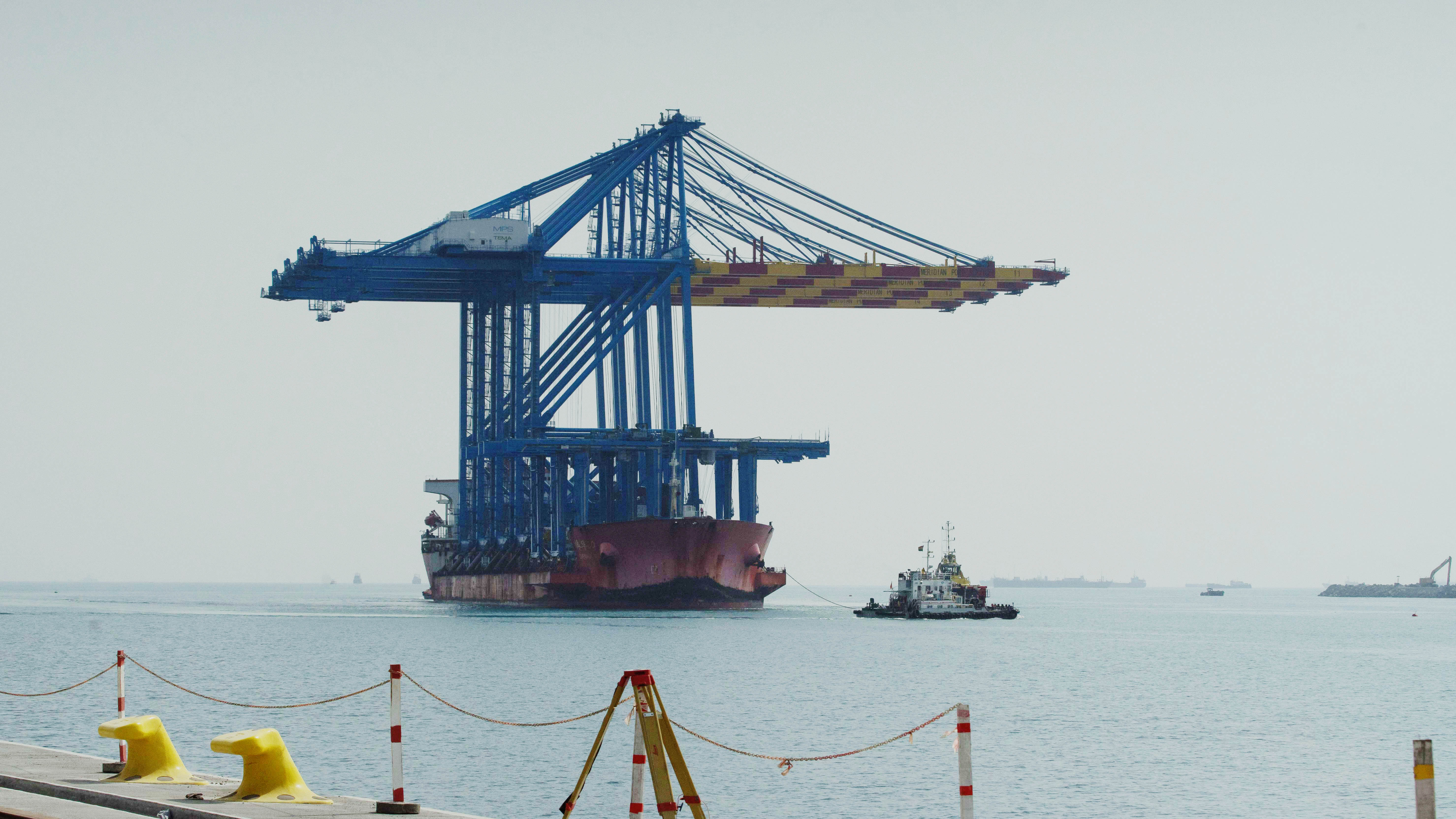 The cranes being guided by a tug boat to the new quay wall