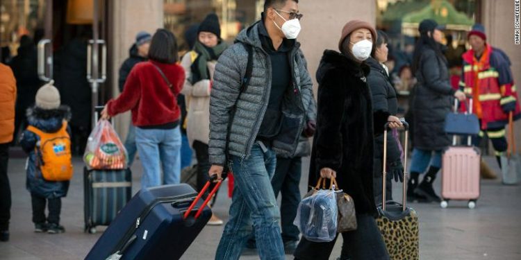 Travelers wear face masks as they walk outside of the Beijing Railway Station in Beijing, Monday, Jan. 20, 2020. China reported Monday a sharp rise in the number of people infected with a new coronavirus, including the first cases in the capital. The outbreak coincides with the country's busiest travel period, as millions board trains and planes for the Lunar New Year holidays. (AP Photo/Mark Schiefelbein)