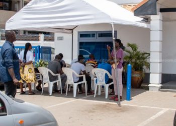 Persons wait outside a bank to comply with the new public gathering advisories