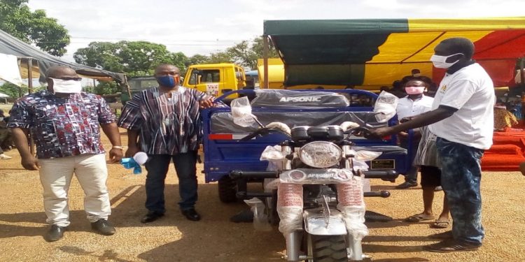 THE M.P (IN SMOCK) FLANKED BY HON. EDWARD OWUSU PRESENTING A TRI-CYCLE TO A BENEFICIARY