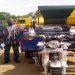 THE M.P (IN SMOCK) FLANKED BY HON. EDWARD OWUSU PRESENTING A TRI-CYCLE TO A BENEFICIARY