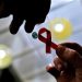 A nurse (L) hands out a red ribbon to a woman, to mark World Aids Day, at the entrance of Emilio Ribas Hospital, in Sao Paulo December 1, 2014. The world has finally reached "the beginning of the end" of the AIDS pandemic that has infected and killed millions in the past 30 years, according to a leading campaign group fighting HIV. United Nations data show that in 2013, 35 million people were living with HIV, 2.1 million people were newly infected with the virus and some 1.5 million people died of AIDS. By far the greatest part of the HIV/AIDS burden is in sub-Saharan Africa. REUTERS/Nacho Doce (BRAZIL - Tags: HEALTH SOCIETY)