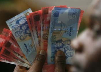 A man holds Ghana's cedi notes in Accra July 3, 2007. Ghana's cedi currency was redenominated on Tuesday, shedding four zeros, in a move intended to make life easier for shoppers and business people fed up of carrying large bundles of cash that make them easy prey for thieves. REUTERS/Luc Gnago
(GHANA) - GM1DVPWYEVAA