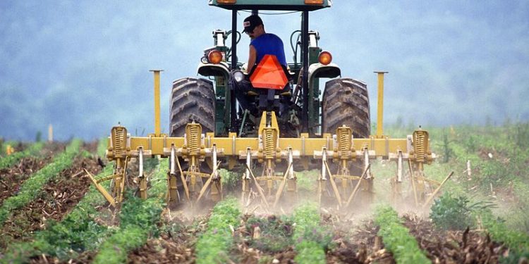 Wiki Commons: Farmer and tractor tilling soil