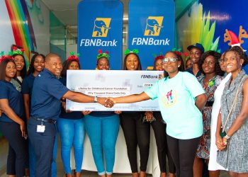 Allen Quaye, Head, Retail Banking, FBNBank Ghana Limited presenting the cheque to Akua Sarpong, Executive Director, Lifeline for Childhood Cancer Ghana. Looking on are a cross section of FBNBank Ghana Staff and Health professionals of the Pediatric Oncology Unit of Korle Bu Teaching Hospital.