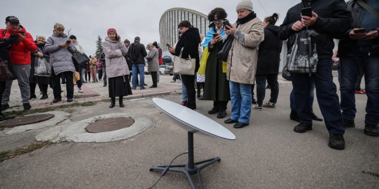 KHERSON, UKRAINE – NOVEMBER 13: Local residents use internet from the Starlink network, set up by Ukrainian army on November 13, 2022 in Kherson, Ukraine. A curfew was introduced in the city from 17:00. until 8:00 a.m. filtration and demining will be carried out. The Ukrainian authorities promise to restore the connection within a few days, there are already the first changes - the connection is gradually appearing in the city center. Electricity and water are also currently unavailable. In all stores, the shelves are almost empty. Only beer and cotton wool are freely available. Pharmacies in the city are also closed, but hospitals are open. (Photo by Andrii Dubchak/Donbas Frontliner via Zaborona/Global Images Ukraine via Getty Images)