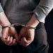 Outlaw's hands locked in handcuffs isolated on black