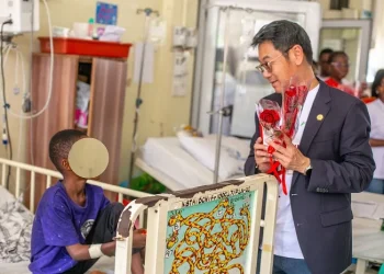Mr. Li presenting chocolate and a flower to a patient in the children's ward