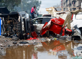 man looks through the wreckages of private vehicles destroyed following heavy rainfall in the Grogan area, popular for automotive workshops and secondhand spare parts, in downtown Nairobi, Kenya