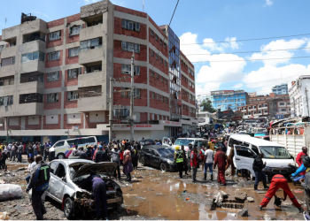People stand around destroyed vehicles following flash floods caused by heavy rainfall in the Grogan area, popular for automotive workshops and secondhand spare parts, in downtown Nairobi, Kenya, March 7, 2026. REUTERS/Monicah Mwangi Purchase Licensing Rights