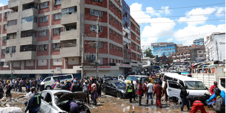 People stand around destroyed vehicles following flash floods caused by heavy rainfall in the Grogan area, popular for automotive workshops and secondhand spare parts, in downtown Nairobi, Kenya, March 7, 2026. REUTERS/Monicah Mwangi Purchase Licensing Rights