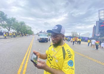 A Ghana fan watches the first half on his phone| The Athletic