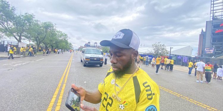 A Ghana fan watches the first half on his phone| The Athletic