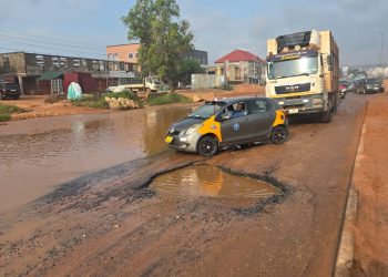Wastewater takes over two lanes of road, while deep potholes worsen conditions